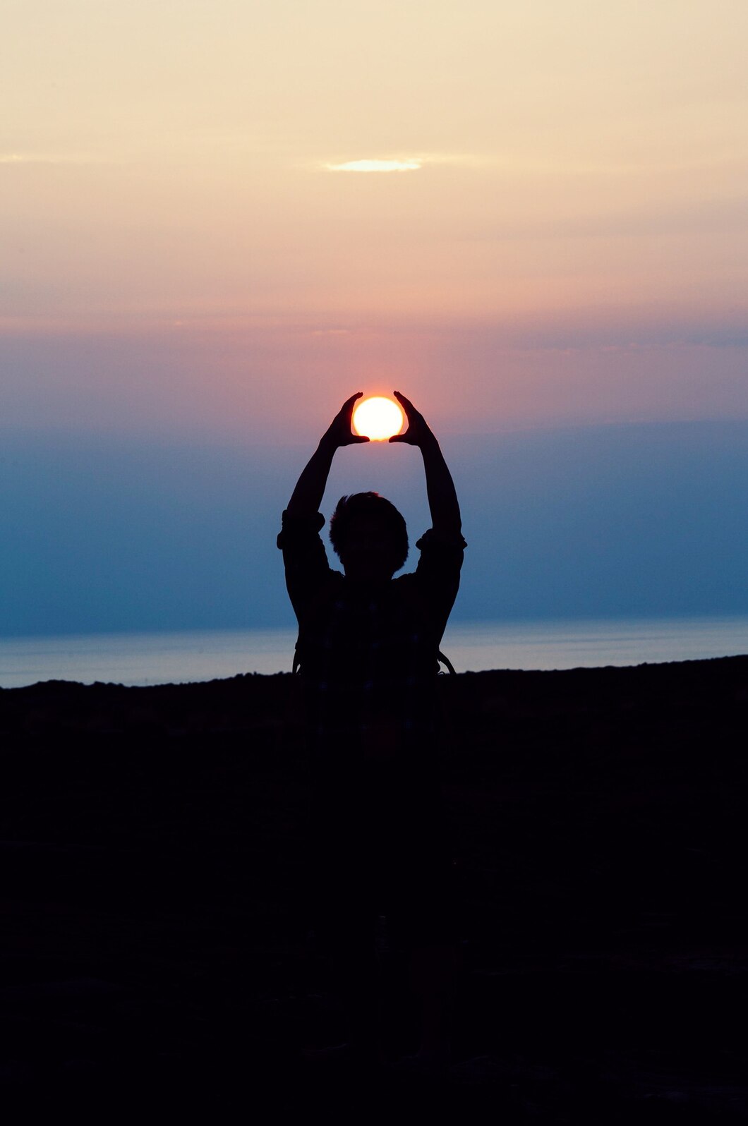 silhouette-person-with-both-hands-his-head-tracing-sun-golden-hour_417767-558